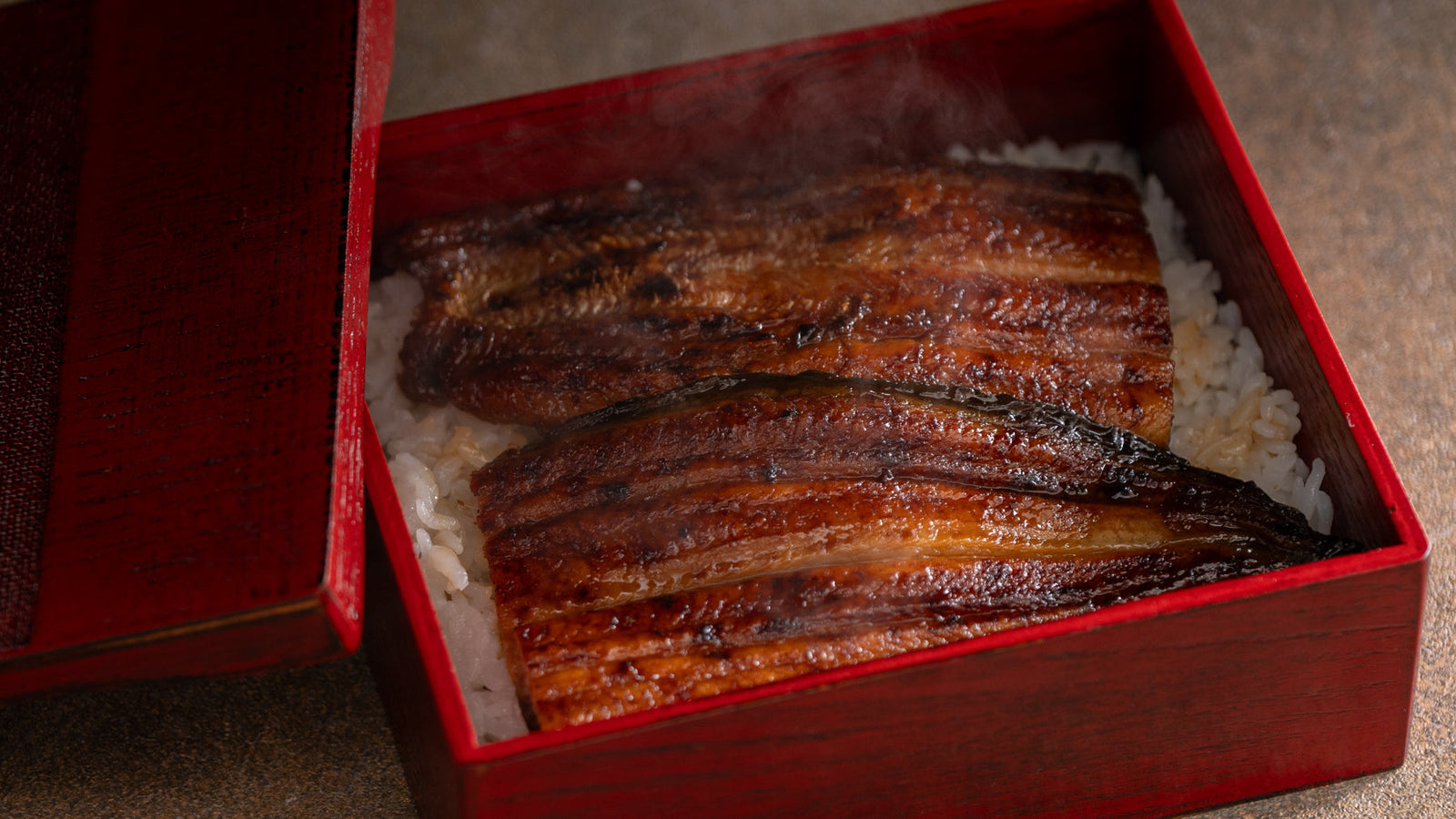 A lacquered unaju box filled with grilled eel over steamed rice