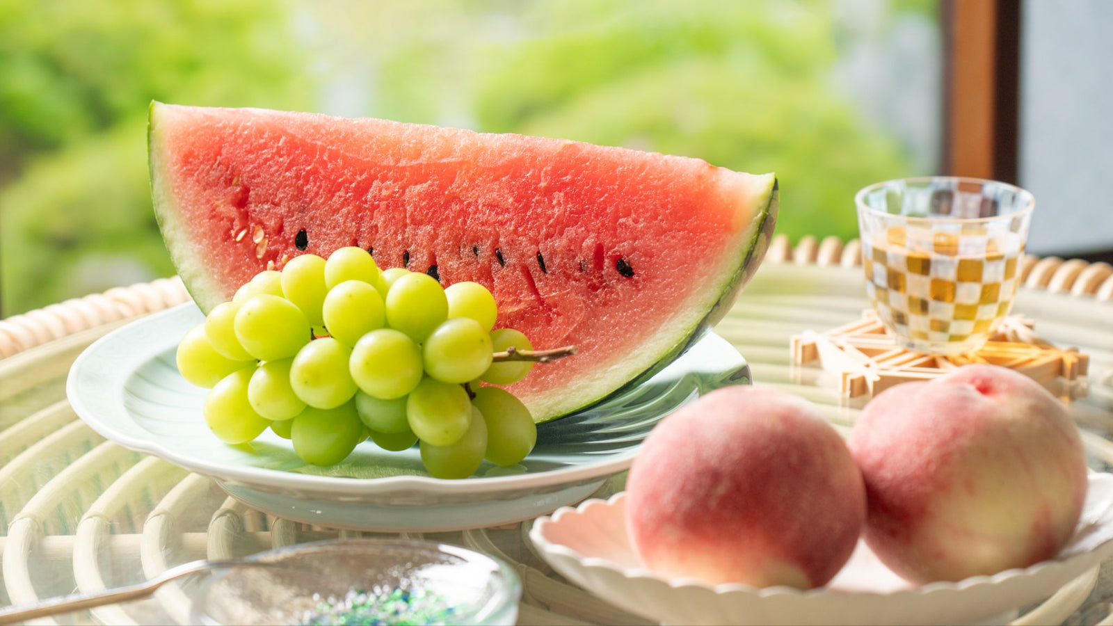 Assortment of Japanese summer fruits including watermelon, Shine Muscat grapes, peaches, and mangoes