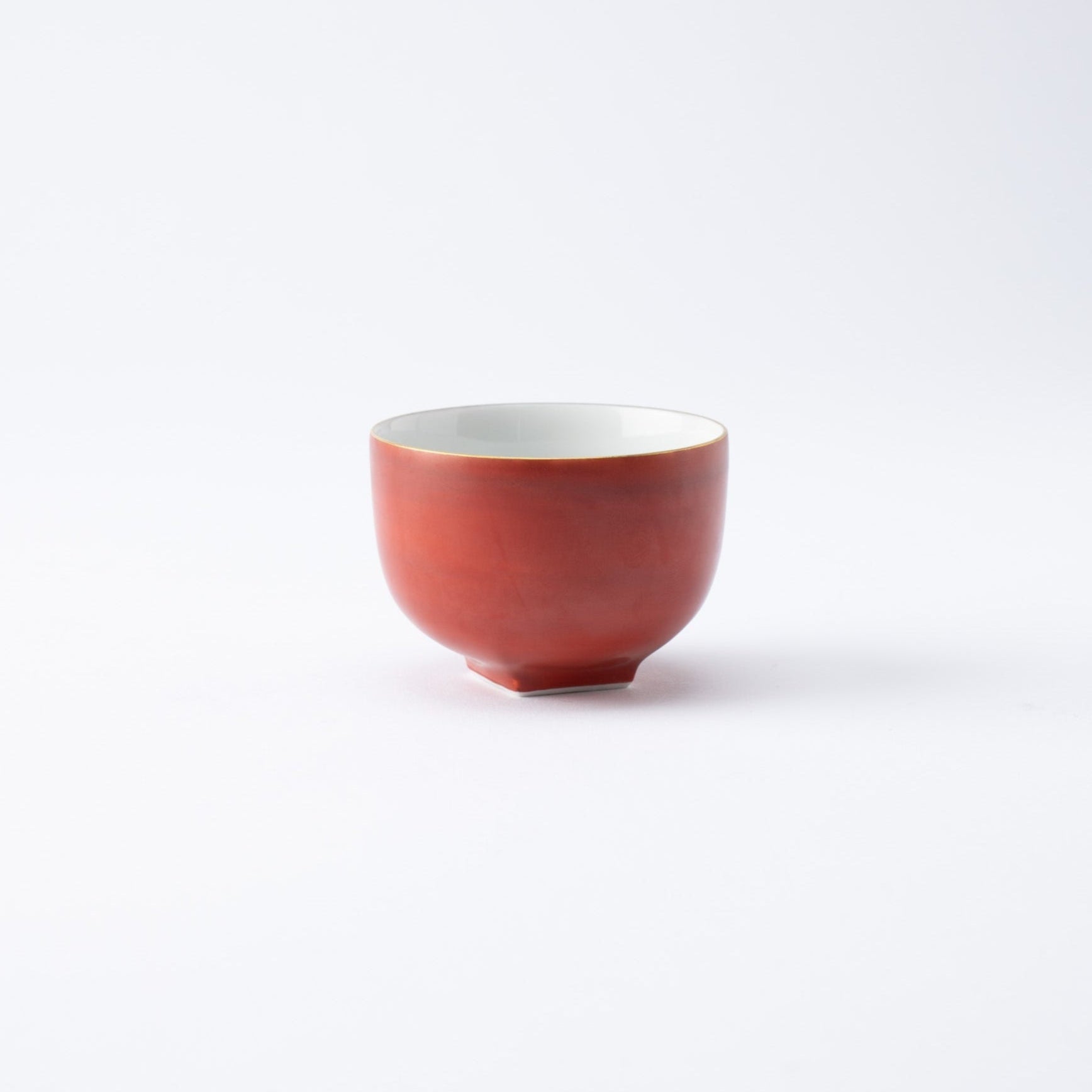 Taza de té japonesa roja con borde dorado