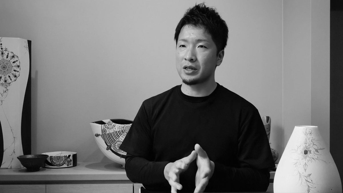 Kanbata Shinya painting extremely fine details onto a ceramic vessel