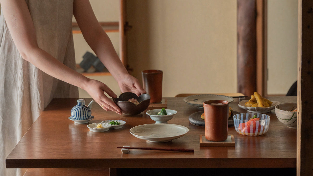 A woman placing summer side dishes on a Japanese-style dining table