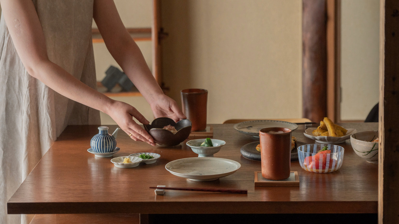 A woman placing summer side dishes on a Japanese-style dining table