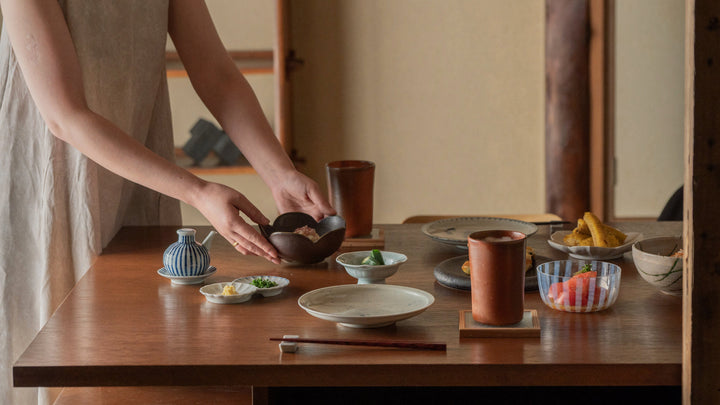 A woman placing summer side dishes on a Japanese-style dining table