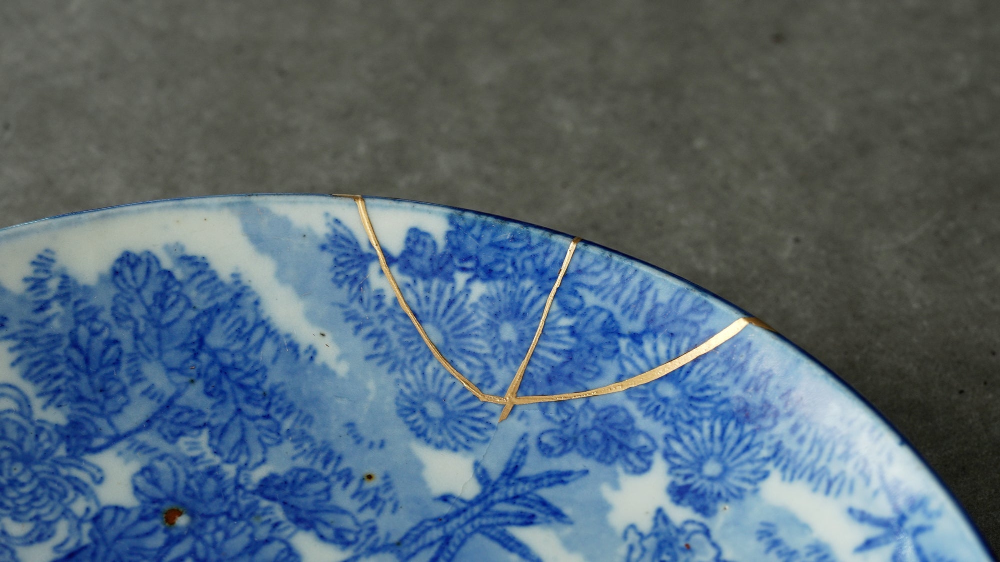 Close-up of a ceramic vessel repaired with kintsugi, showing the gold-joined seam along the crack.