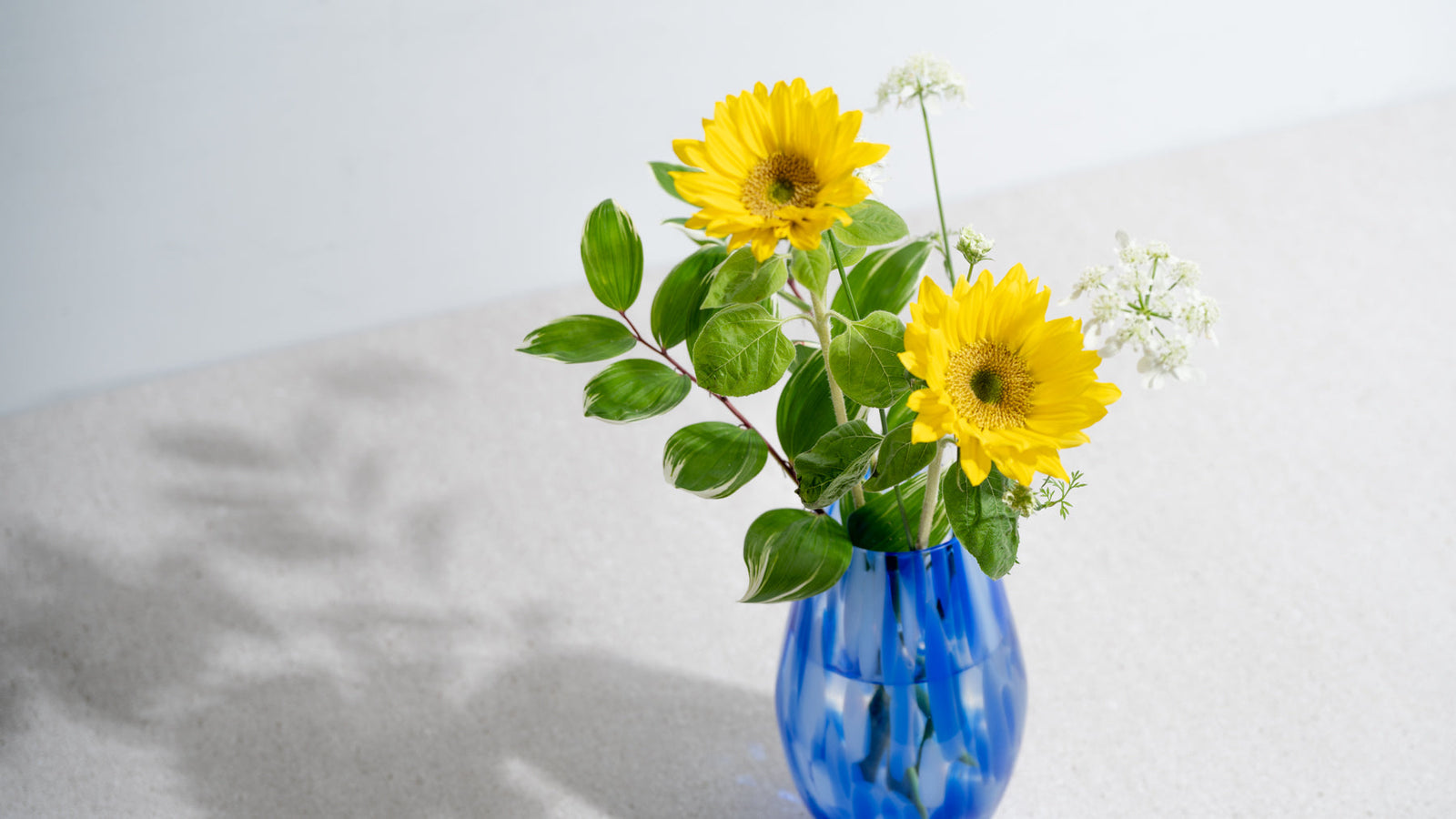 Sunflowers arranged in a clear glass Japanese flower vase, styled for summer.